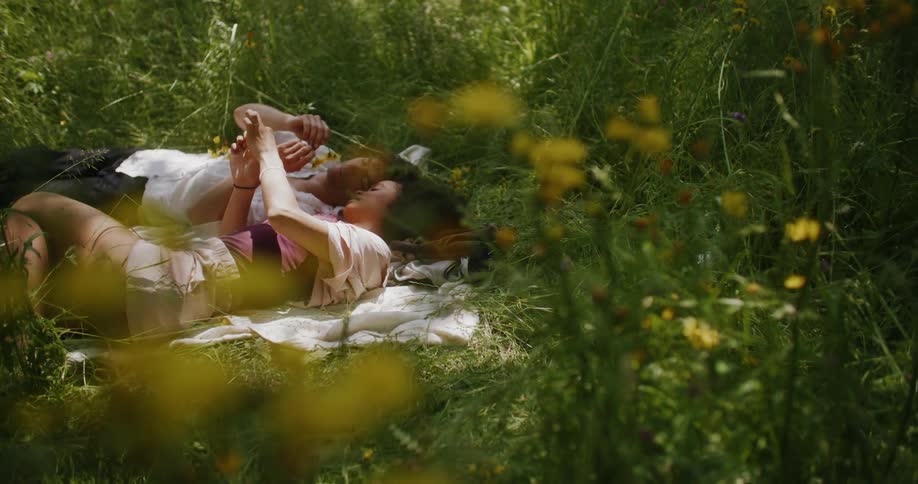A man and woman lay together in the grass