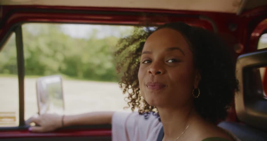 A woman is sitting in a car and is smiling
