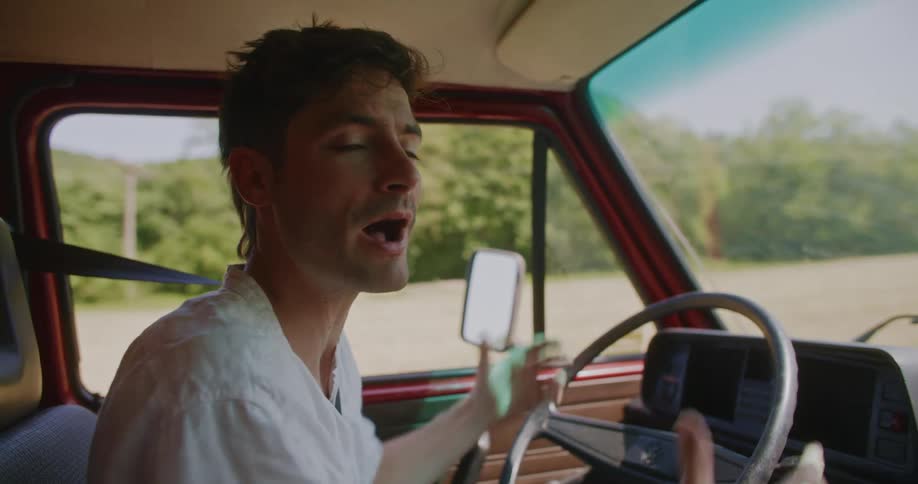 The view is of a portrait of a man that is yelling inside of his car