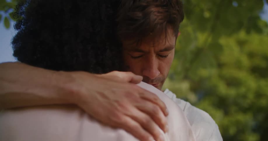 Two people are standing outdoors and hugging