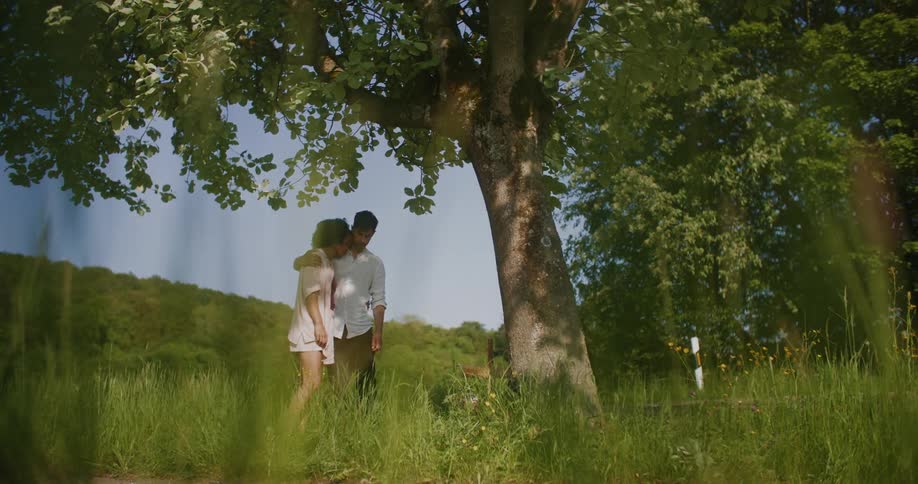 A man and woman standing together under a tree hugging each other