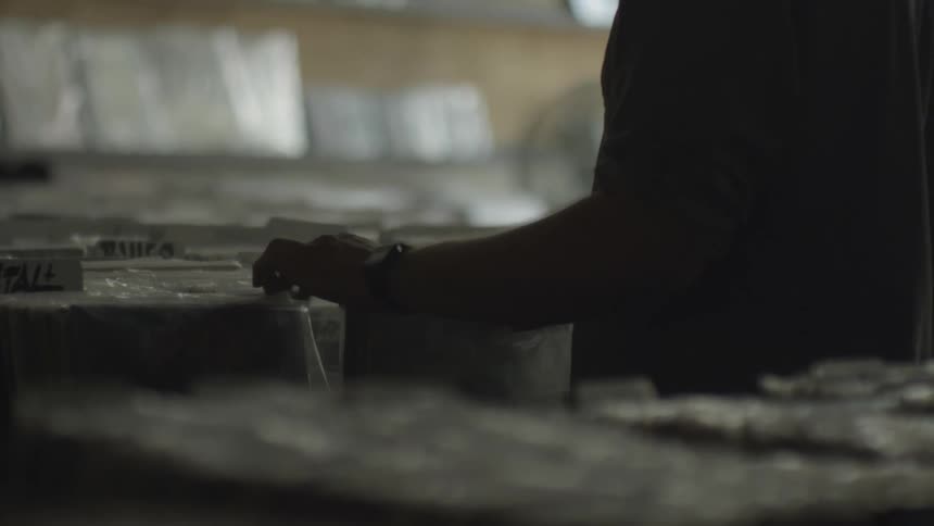 A close up of a man looking through records wrapped in plastic in a record store