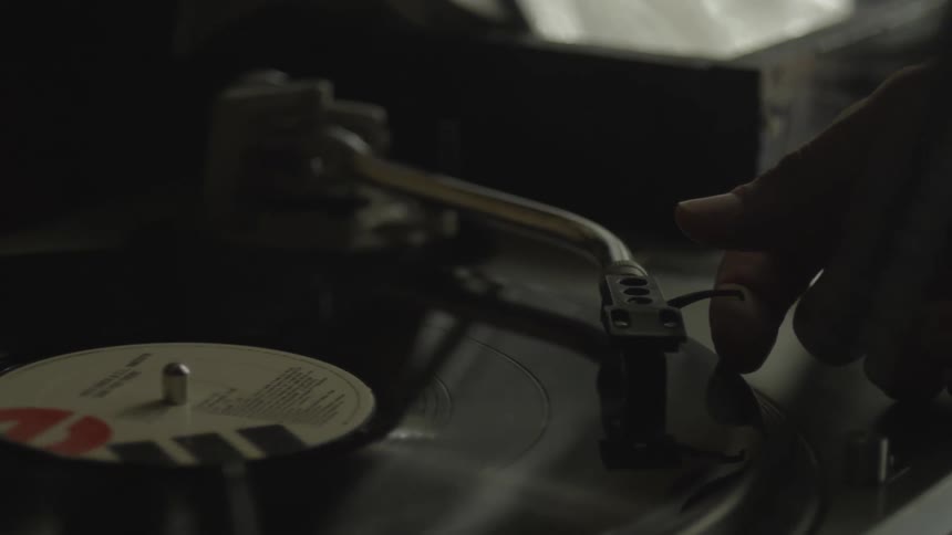 Close up of a cord and a record on a record player as a person moves the dial off and removes the disc