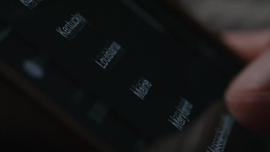 Close up of a persons hands scrolling on a phone screen looking at states