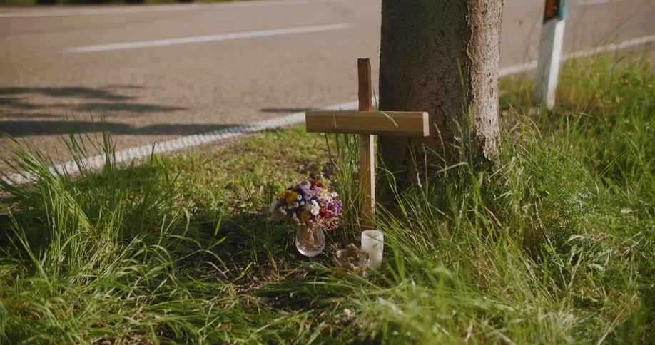 A cross with candle and flowers in a grassy landscape as a symbol of religious worship