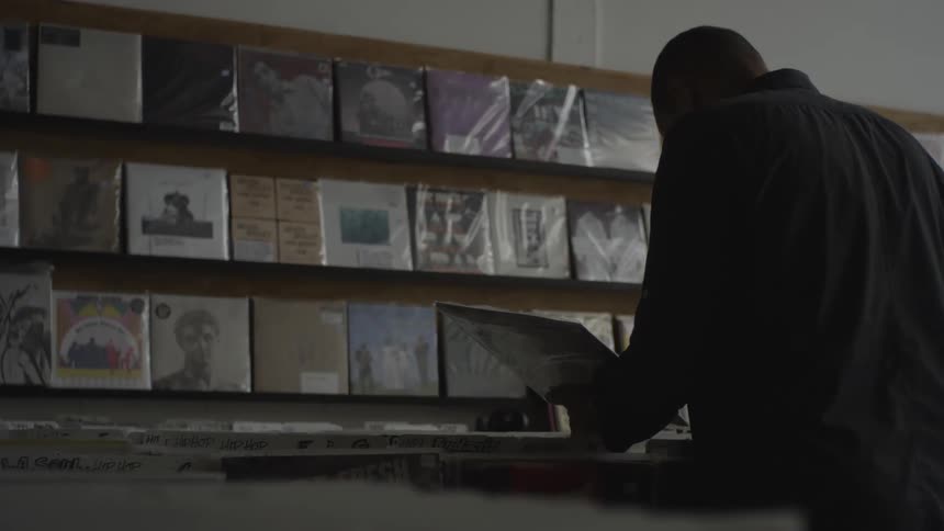 Man stands looking at album jacket while browsing in music store