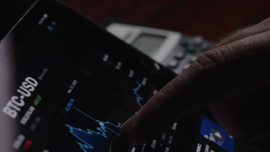 Person tracks bitcoin exchange rate and enters numbers on calculator