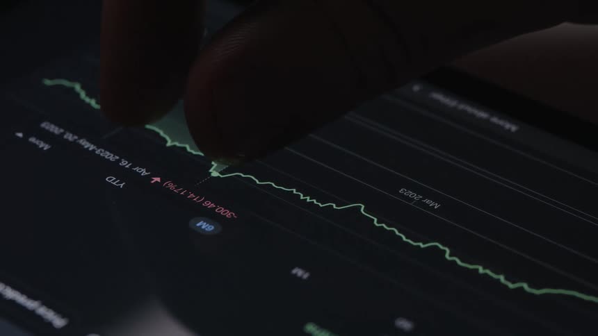 Person touching a tablet screen with their fingers to check stock prices