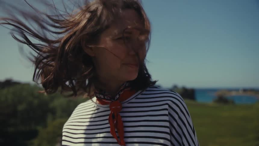 Woman turns to talks while she stands overlooking scene on windy day