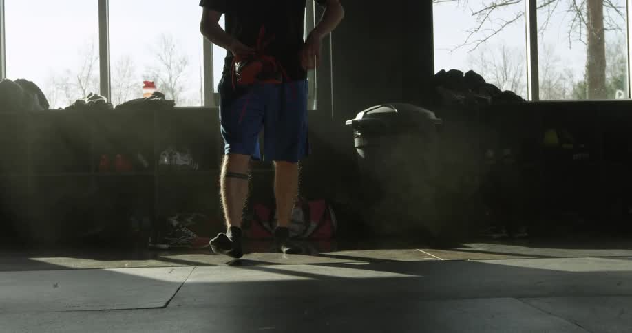 A man carrying athletic shoes is walking across a floor in a gym