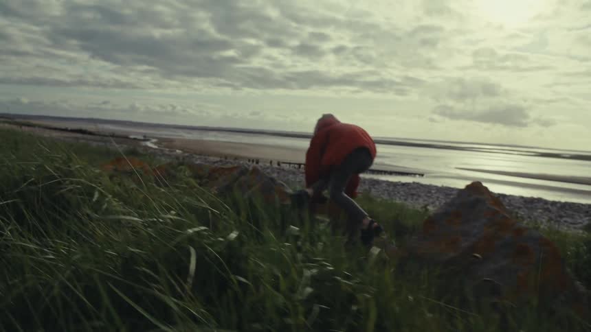 Young child climbs on rocks next to a beach