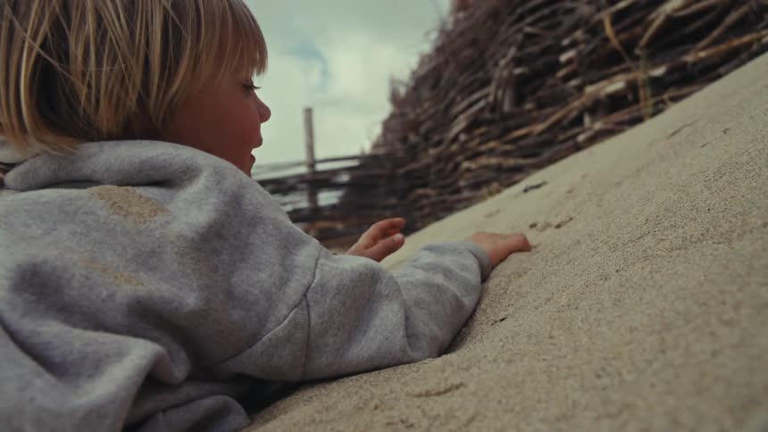 Young child is playing in the sand on the beach