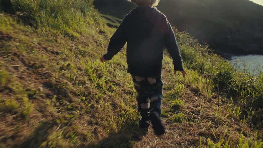 A child is running on a trail by the shore