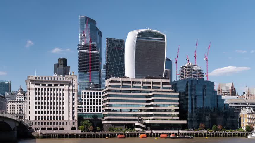 A time lapse of city buildings built next to a waterway that has boats traveling in it