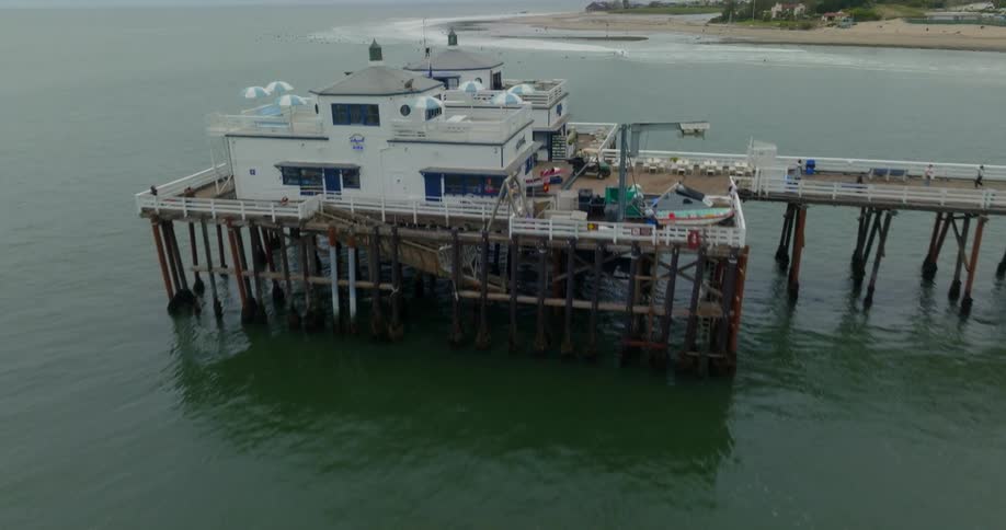 An aerial shot of the Malibu pier reveals surfers in the background