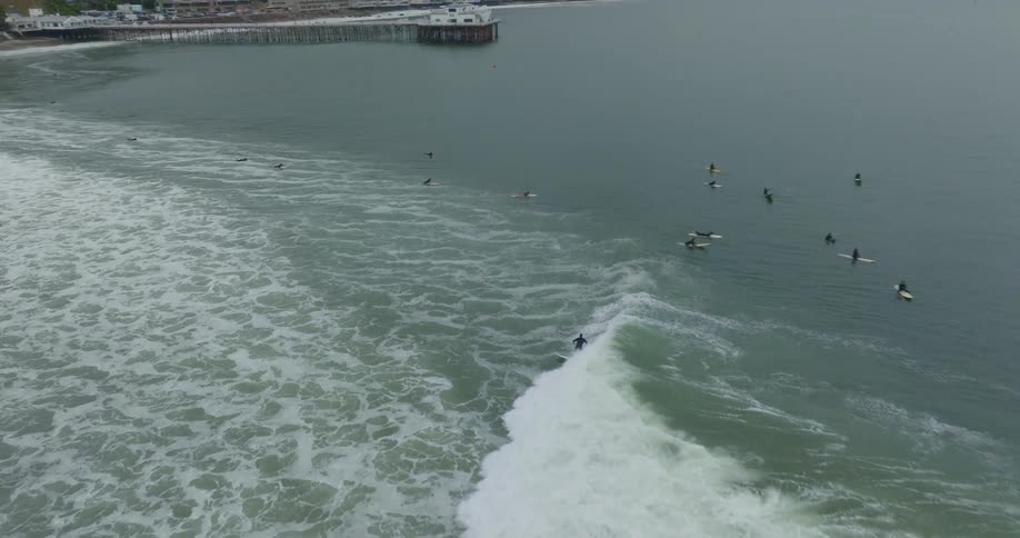 A surfer rides a wave as the camera chases him
