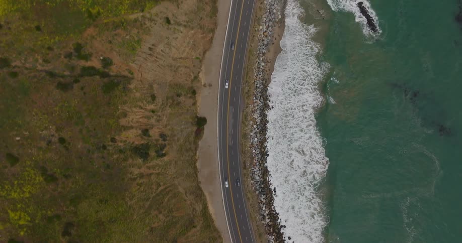 A top down aerial view of cars driving along PCH on the coast of Los Angeles California