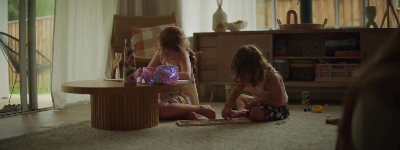 Two little girls inside the living room doing different fun activity while sitting near the table