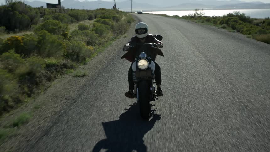 A person rides a motorcycle as a car goes the opposite way