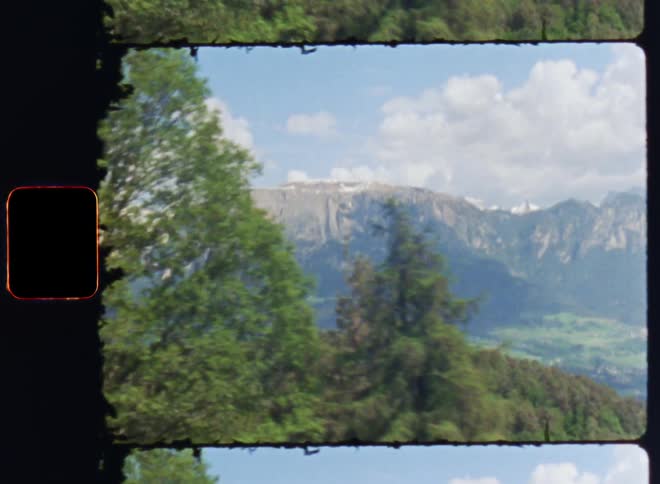 Travelling shot of a mountain range next to a valley and a forest