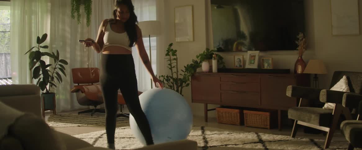 Pregnant woman listening to music practicing yoga indoors