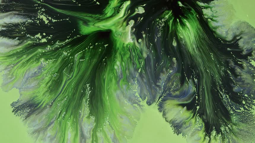 Neon green glows in the black as it spreads across the soft green and gray colors on the surface as they blend