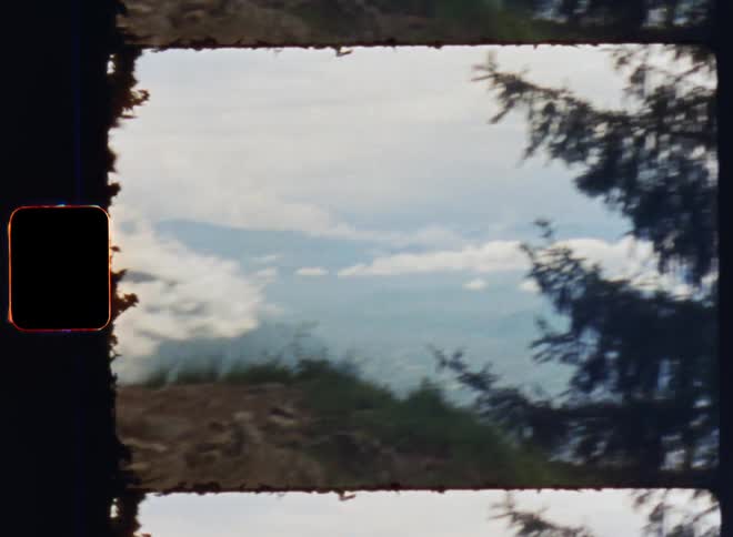 A bench is placed on top of a mountain with rocks and trees