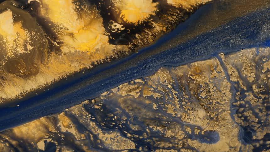 A dark glittering liquid flows like a stream through a yellow textured surface