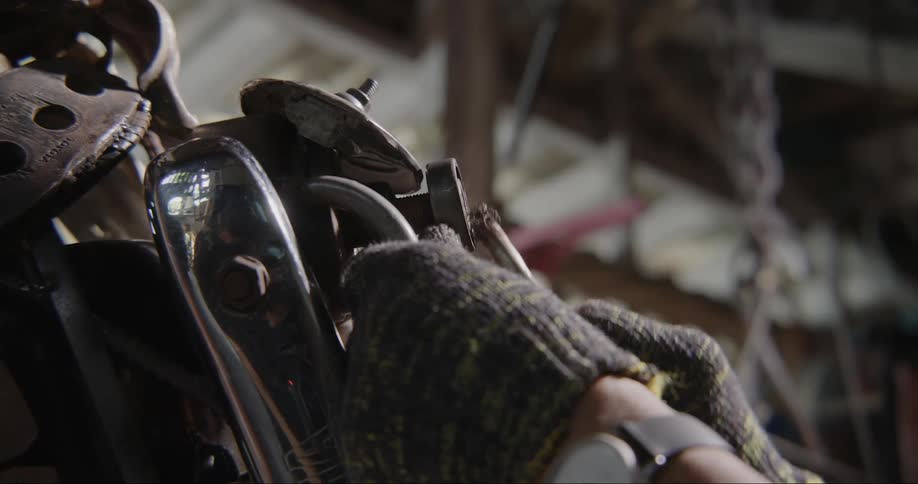 Someone in a hand glove working on an engine