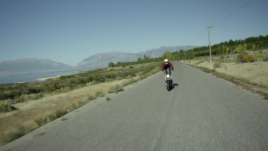 A motorcyclists performs a stunt by standing on his moving bike
