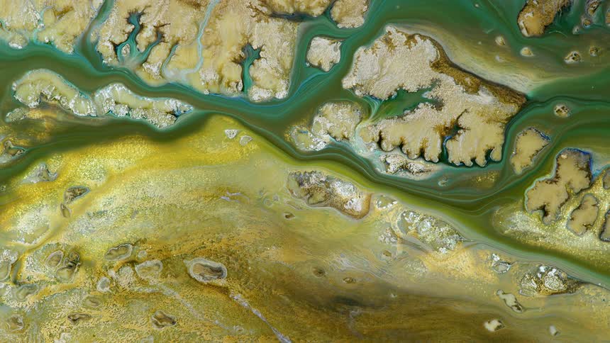 Green liquid flows through a golden textured surface like a river through a landscape