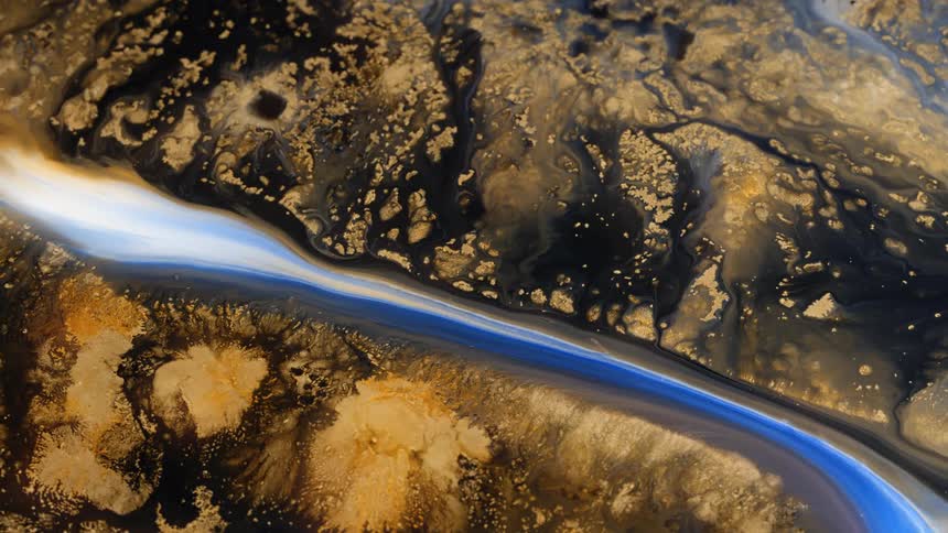 A wide view of blue and gold glitter paint flows through a cavern on canvas