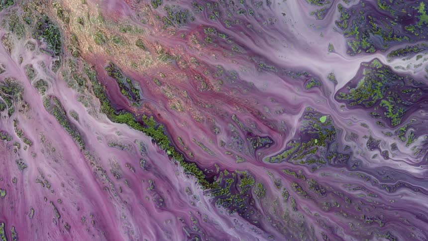 White liquid spreads as it flows across a green textured surface in this surreal landscape