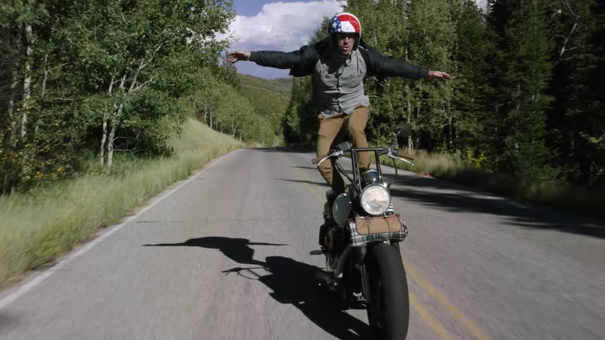 A man stands on his bicycle while riding it