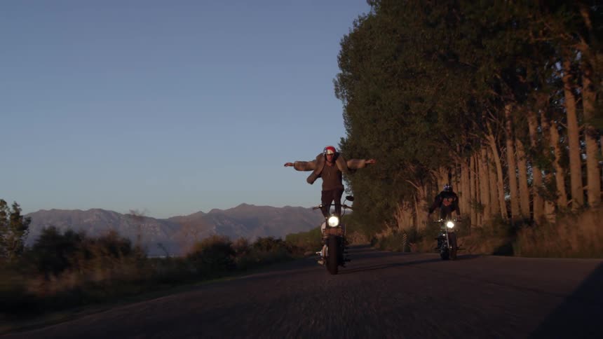 Two people stand on their motorcycle riding
