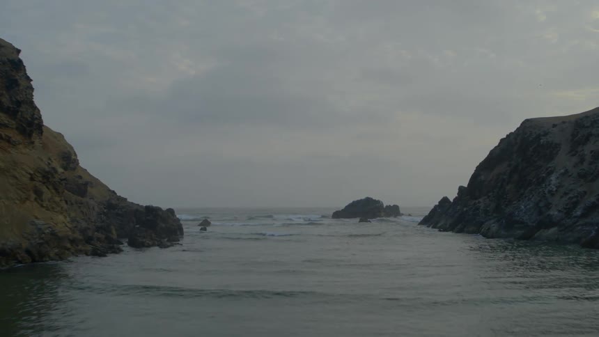 Large rocks are in the water by the coast