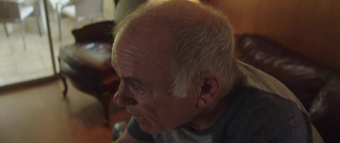 Elderly man standing up from the couch and cheering in his living room