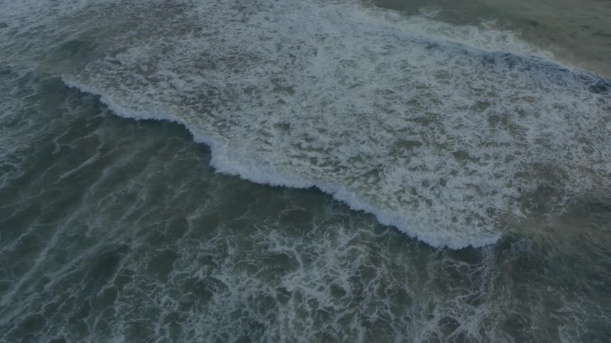 Ocean waves near a rocky coastline during the day