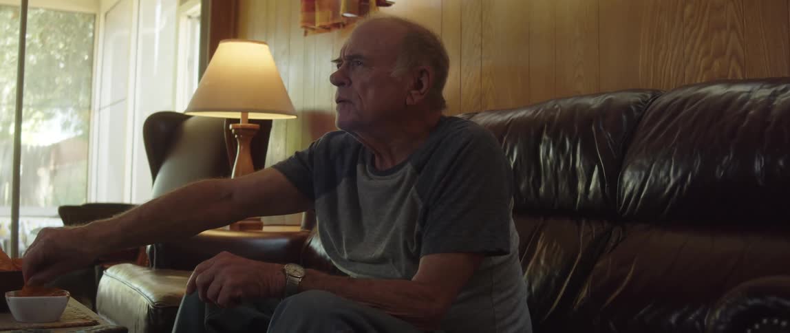 Man sitting on the couch excitedly watching sports on tv while enjoying appetizers