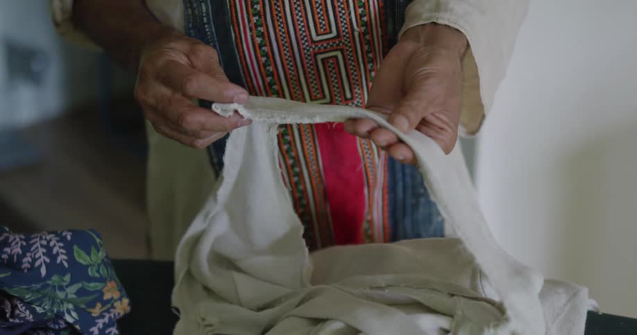 Two women stand handling fabric