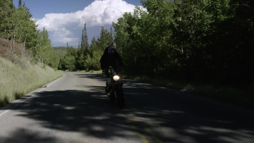 A man balances on his motorcycle in a rural area