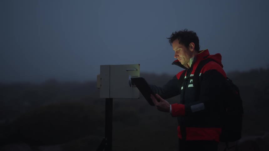A man checks his tablet before continuing his hike