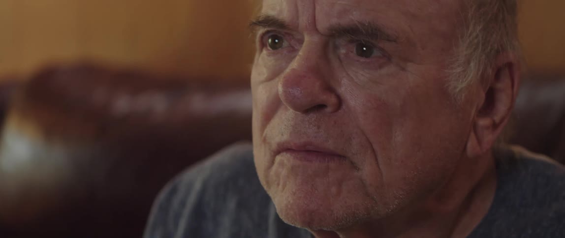 Elderly man carefully watching something then cheering and smiling