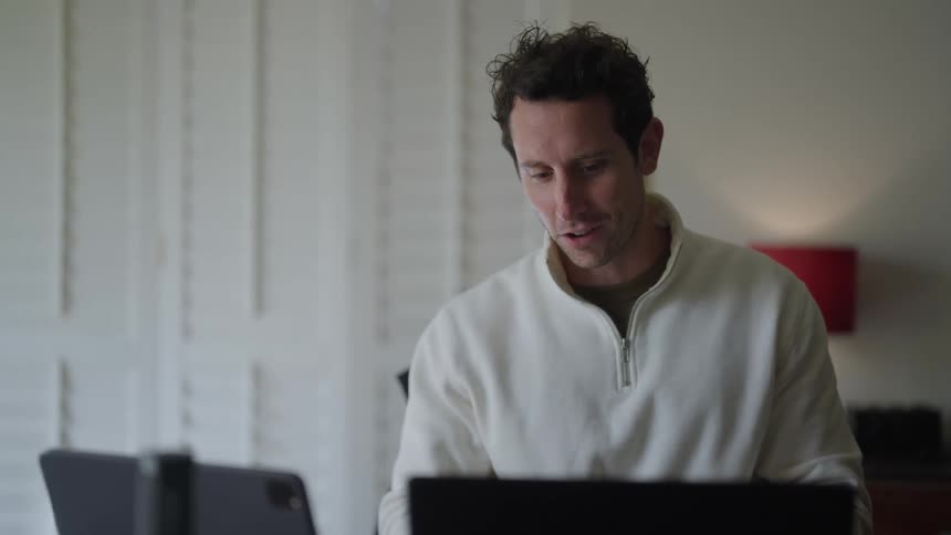 Man sitting in front of a computer and a tablet chatting