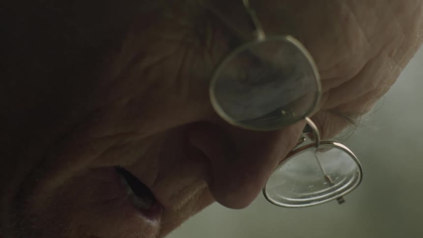 Closeup shot of an elderly white mans face wearing glasses