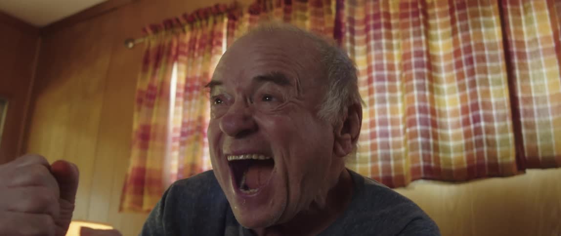 Man sitting on the couch watching sports on tv getting up celebrating and clapping