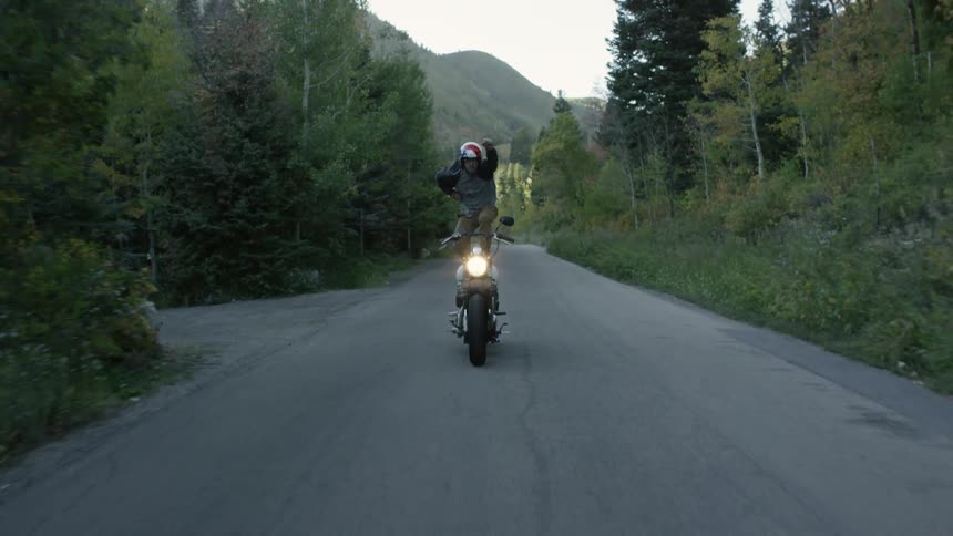 A man is standing as he rides on a motorcycle