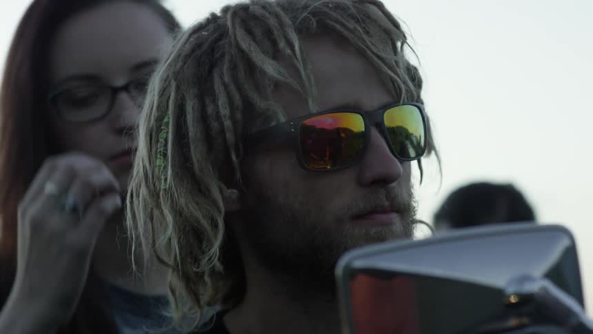 Man puts on sunglasses while sitting on a motorcycle with a woman