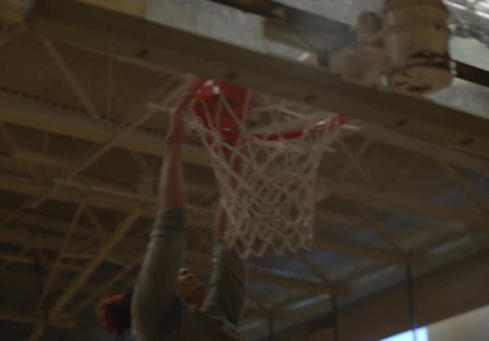 Two men are playing basketball on a basketball court in a gym