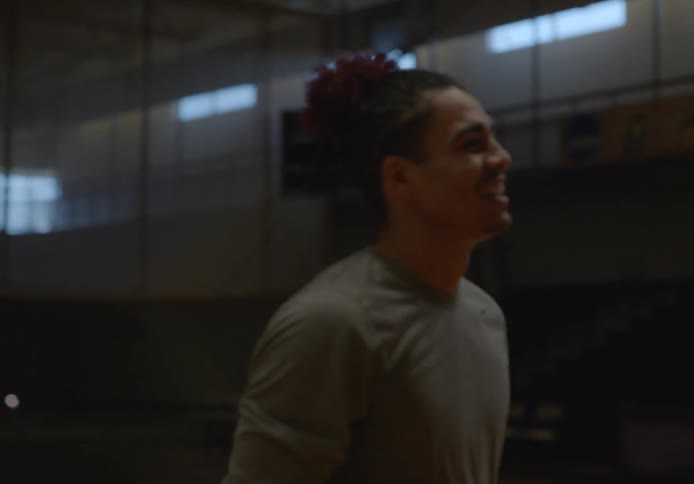 Smiling teenager practicing basketball on an university basketball court